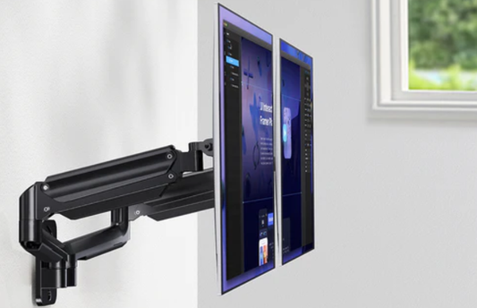 A wall-mounted monitor arm holds two computer screens.